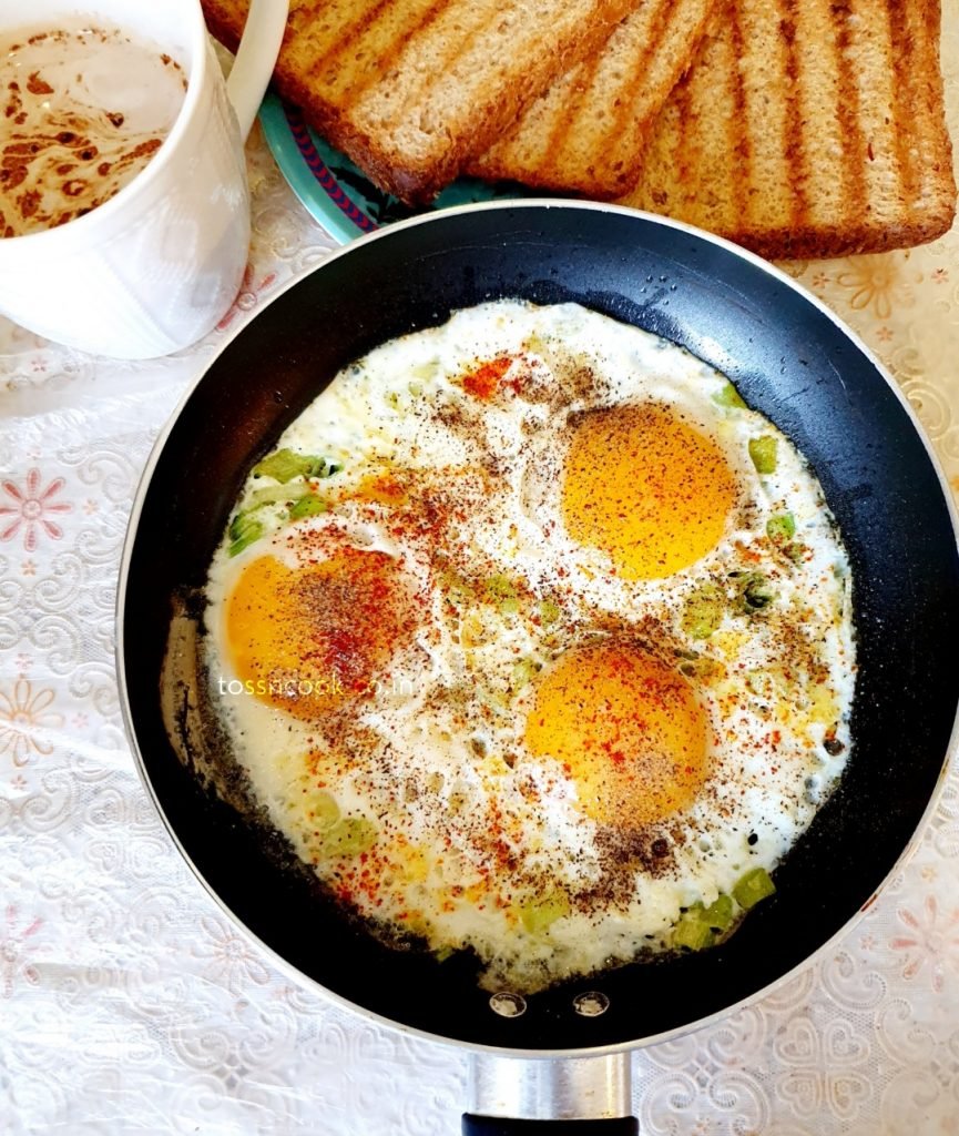 Masala Fried Eggs Masala Fried Eggs in a round pan with coffee and bread toast in the side